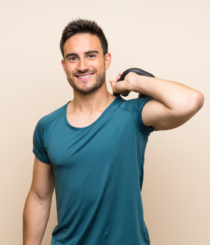 Photo of a muscular man holding a kettle bell behind his back