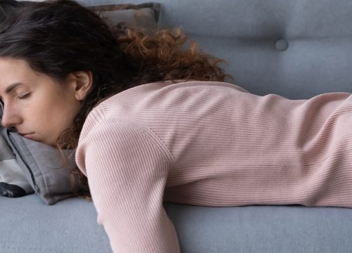 Photo of a woman experiencing low energy, sleeping on her sofa